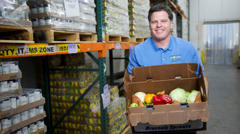 A person holds a box full of vegetables