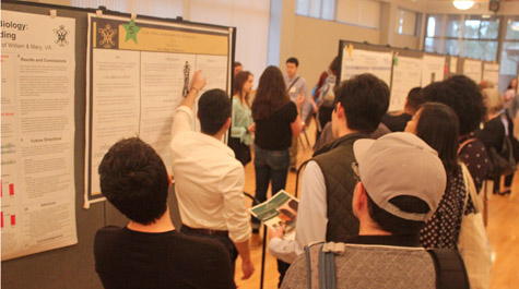 People watch as someone talks about a poster that is hanging on a wall