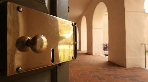 A door with a brass lock is ajar, and the Wren portico can be seen in the background