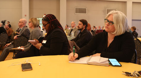 People taking notes at a table while listening to presentation