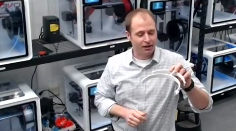 Jonathan Frey looks over a freshly printed visor portion of a face shield 