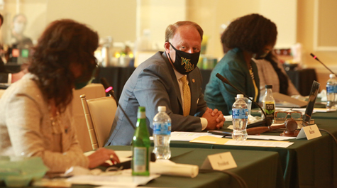 Three people wearing masks sit at a table