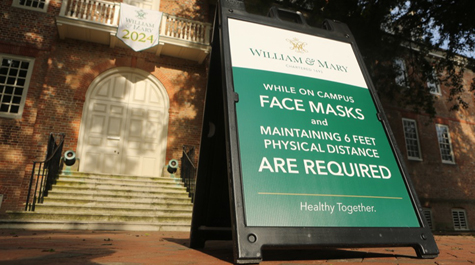 A sandwich board sign outside of the Wren Building says masks are required on campus