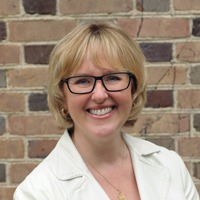 Ginger Ambler stands in front of a brick wall