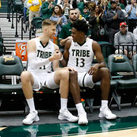 Andy Van Vliet and Nathan Knight shake hands while sittting on the bench