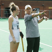 Tess Ellis talks to a field hockey player on the field