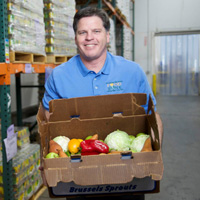 A person holds a box full of vegetables