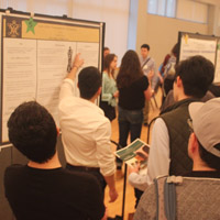 People watch as someone talks about a poster that is hanging on a wall