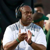 Mike London clapping his hands on the football field sideline