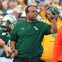 Mike London on the sidelines of a football game with others around him