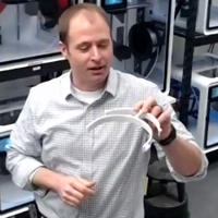 Jonathan Frey looks over a freshly printed visor portion of a face shield 