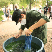 A student dunks a piece of cloth into a large container of liquid