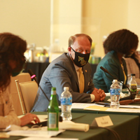 Three people wearing masks sit at a table