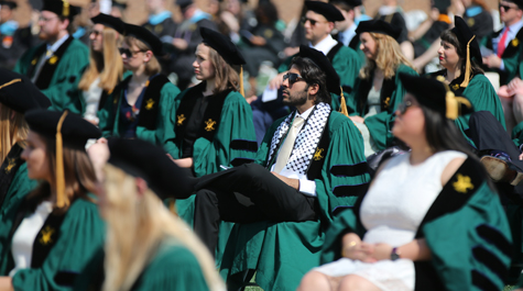 People wearing caps and gowns sit in chairs