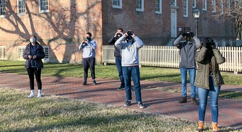 People look toward the sky with binoculars