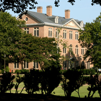 A large brick building seen through shrubbery