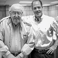 Two man stand arm in arm in a newspaper newsroom