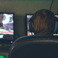 A person wearing headphones sits at a computer
