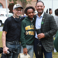 Three people stand together for a photo outside