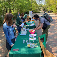 People wearing masks stand next to a table in an outdoor location