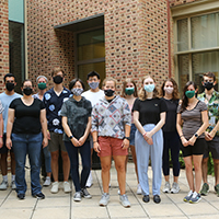 A team of student researchers and faculty mentor stand in group outdoors