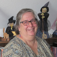 Barbette Spaeth with witch dolls on shelf behind her