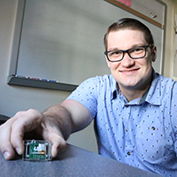 A student holds a device with a computer chip