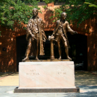 Part of the law school building with statue in front and trees in bloom