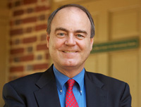 Steve Hanson in a suit stands in front of a brick wall