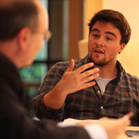 A student gestures while talking with a professor