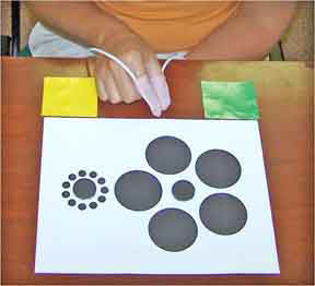 Apparatus attached to thumb and forefinger allow psychologists to measure the grip aperture of subjects as they reach for the center circles of an Ebbinghaus array. Courtesy Peter Vishton.