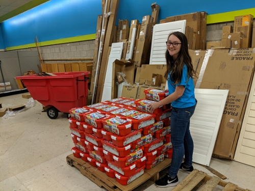 Volunteer smiling at camera with Restore donations