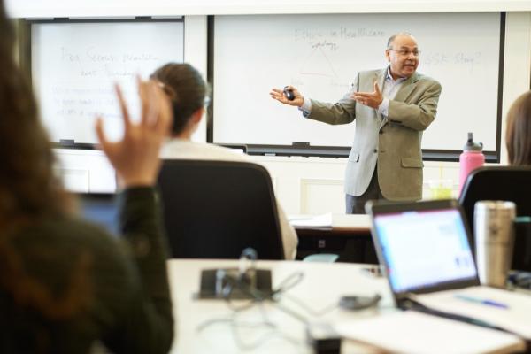 A professor speaking in front of a dry erase board