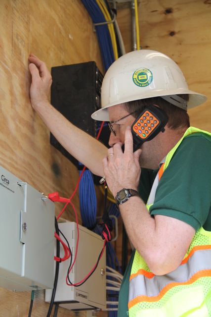 Using a test phone, Jolly confirms that the elevator phone service is working.
