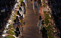 Wren Courtyard lit at night filled with, with new students walking down a brick path lined with members of campus offering high-fives