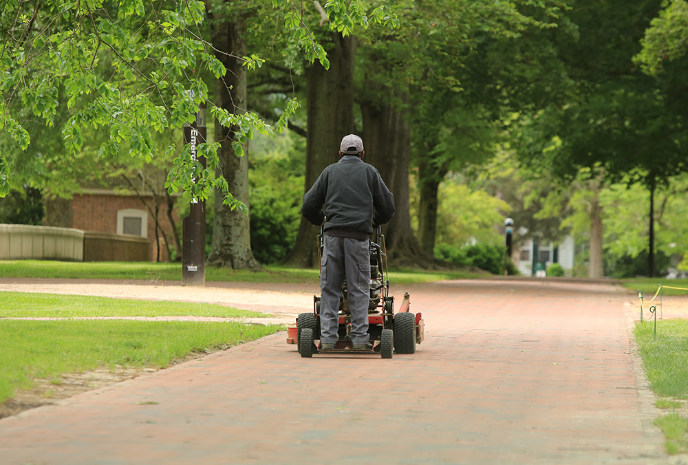 A William & 玛丽 employee operating a lawn mower.
