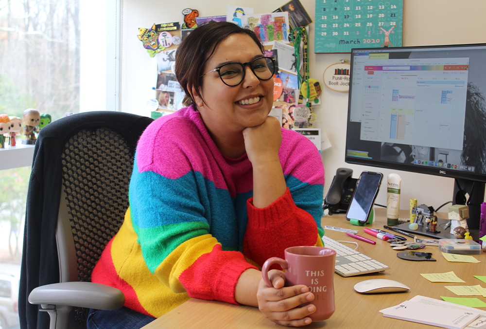A William & 玛丽 library employee smiles for a photo at their desk.