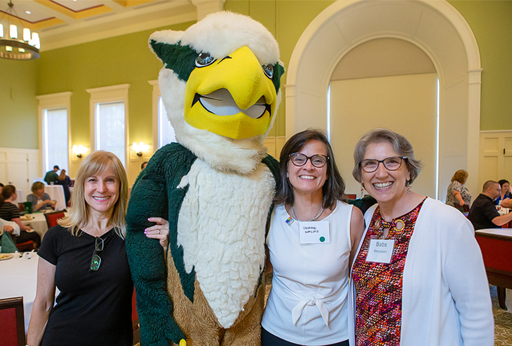 Three William & 玛丽 employees pose with the university mascot.