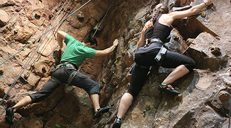 Two students climb the rock wall at the student recreation center