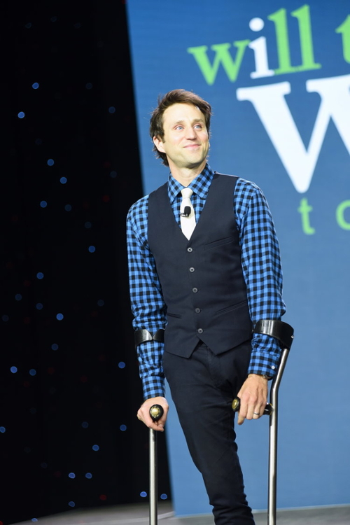 Josh Sundquist '06 on a stage with a projection screen behind him