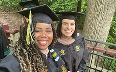 Two smiling graduates pose for a selfie on the Crim Dell bridge