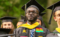 A group of graduates in Commencement attire and colorful stoles prepare to walk to the Commencement ceremony